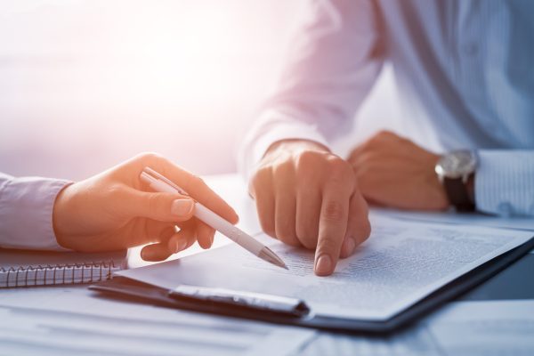 Business people negotiating a contract. Human hands working with documents at desk and signing contract.